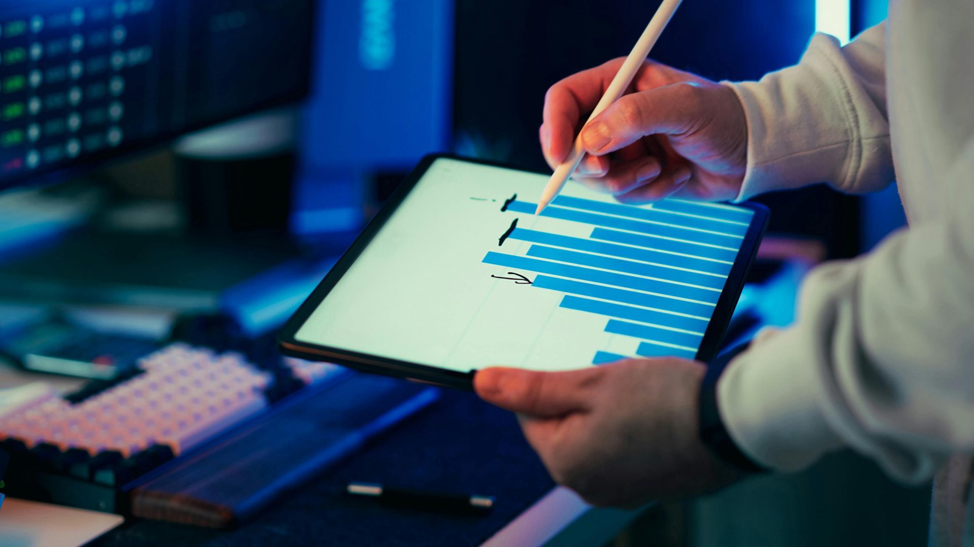 Eine Person, die in einer Büroumgebung mit einem Stift auf einem Tablet ein Geschäftsdiagramm anzeigt.