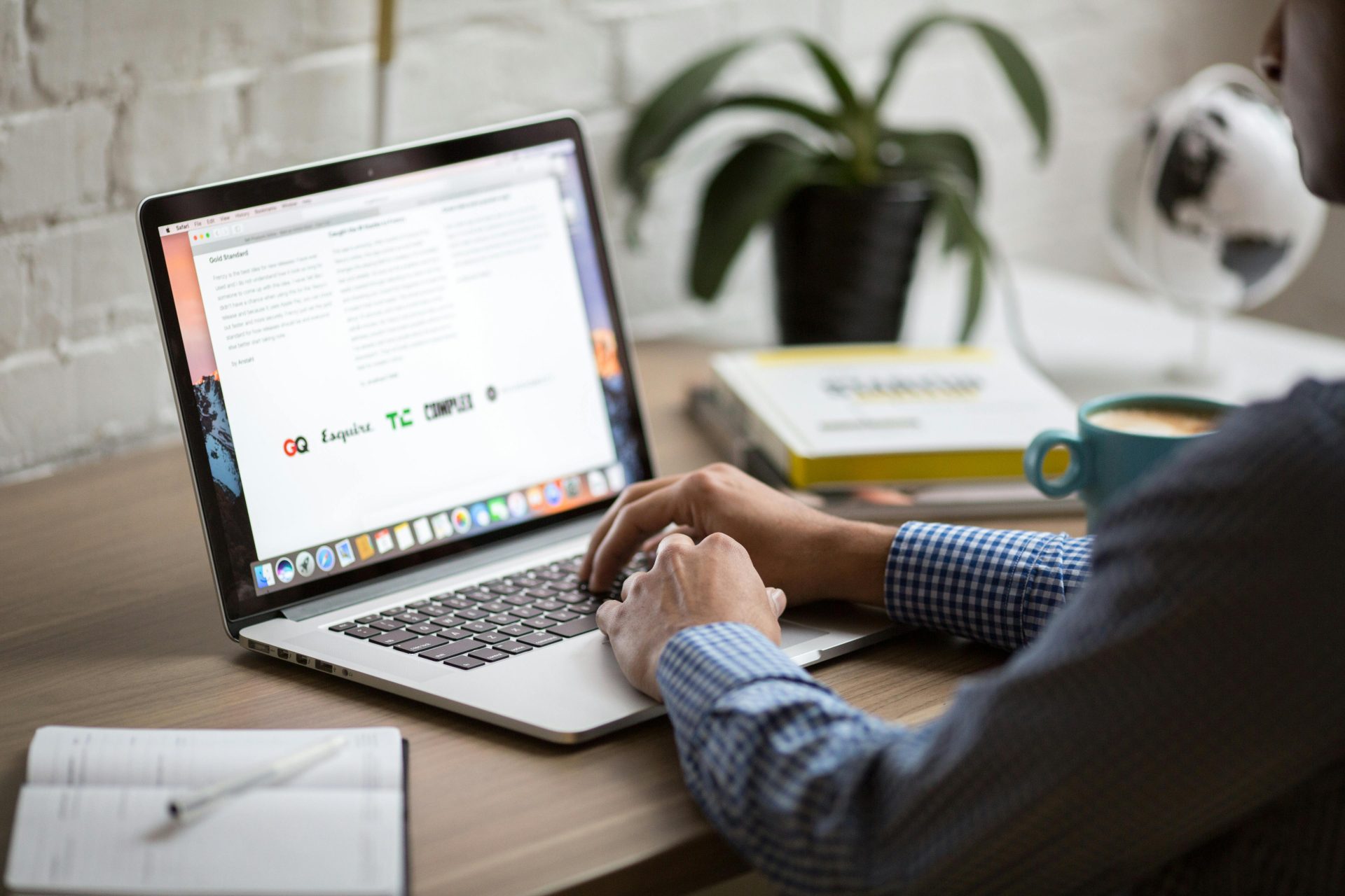 Ein Mann arbeitet an einem Laptop an einem Schreibtisch mit einer Tasse Kaffee – ein Beispiel für mobiles Arbeiten in einem modernen Büroumfeld.