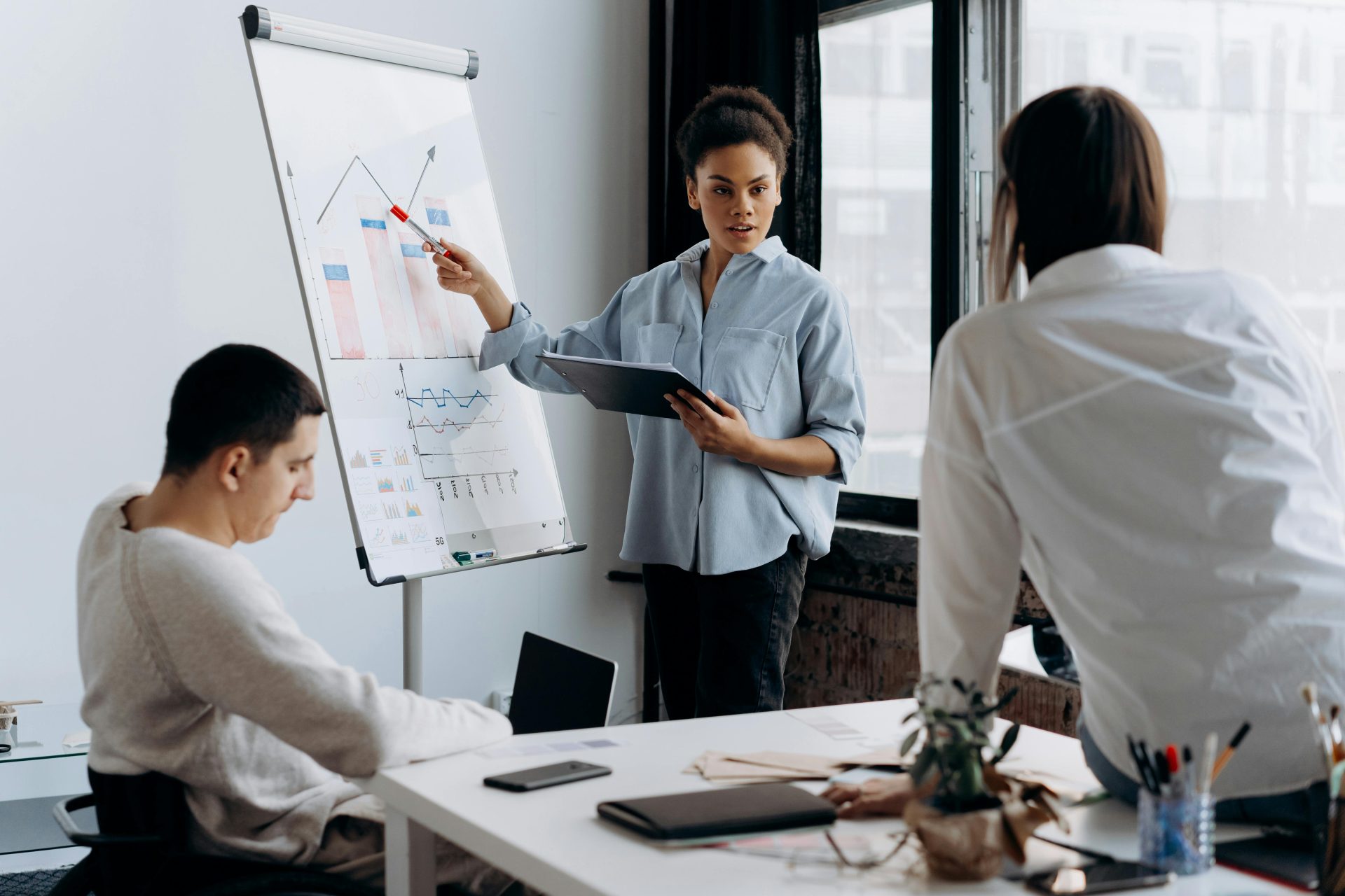 Ein Business-Team diskutiert in einem modernen Büroumfeld die Strategie anhand einer Präsentation.