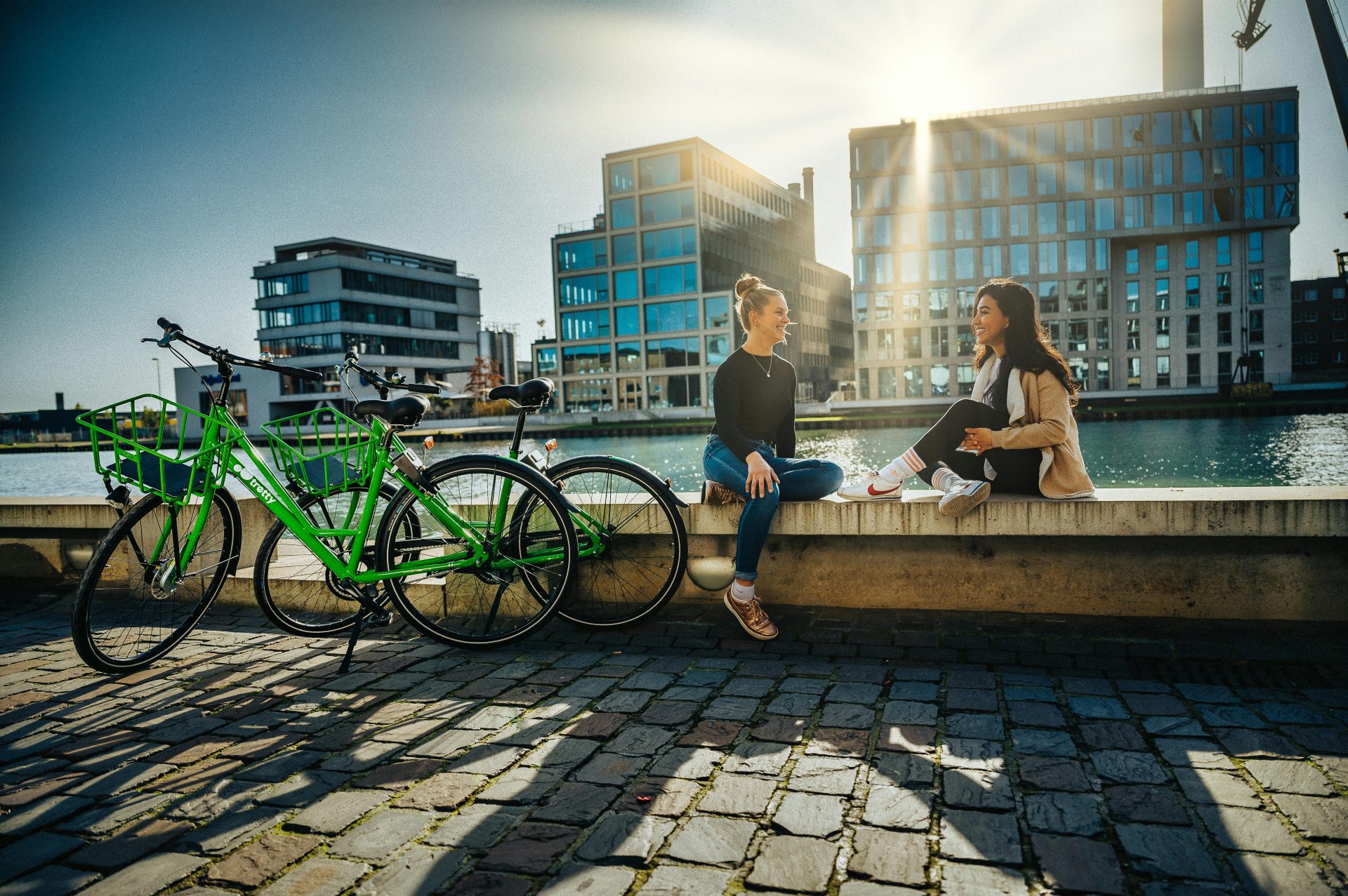 Zwei Freunde genießen einen sonnigen Tag am Wasser mit Fahrrädern in Münster.