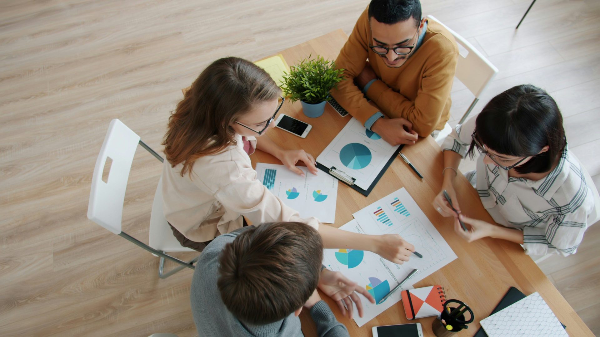 Ein diverses Team arbeitet gemeinsam an einem Tisch mit Diagrammen.